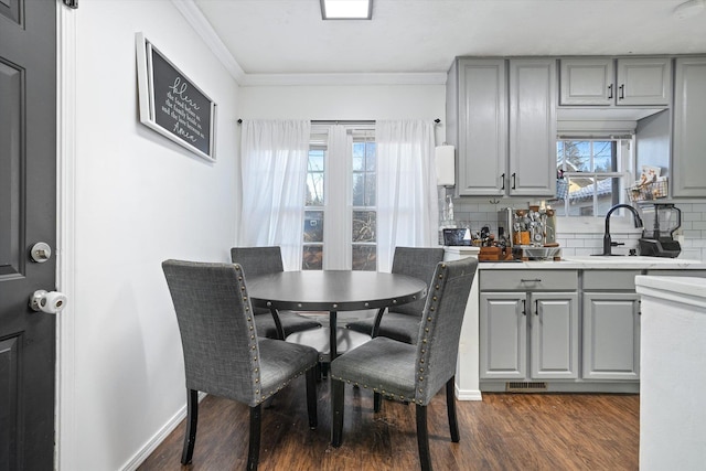 dining space with sink, crown molding, and dark wood-type flooring