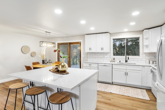 kitchen with white appliances, pendant lighting, and white cabinets