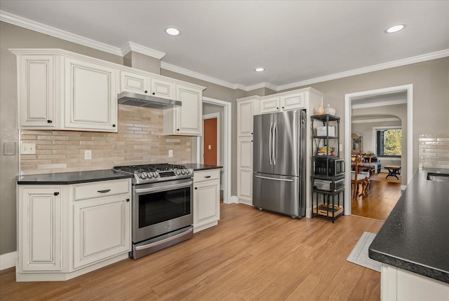 kitchen with appliances with stainless steel finishes, backsplash, white cabinetry, light wood-type flooring, and ornamental molding