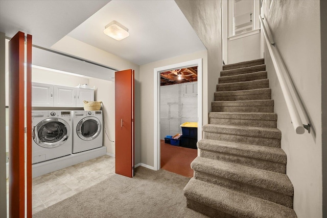 clothes washing area with washer and dryer, cabinets, and light carpet