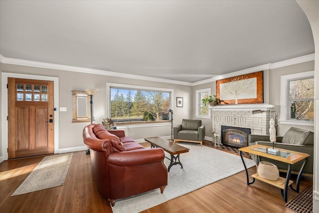 living room featuring a brick fireplace, wood-type flooring, and ornamental molding