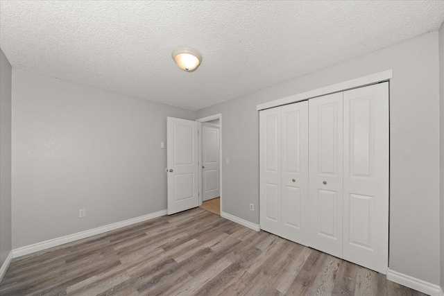 unfurnished bedroom with light hardwood / wood-style floors, a textured ceiling, and a closet