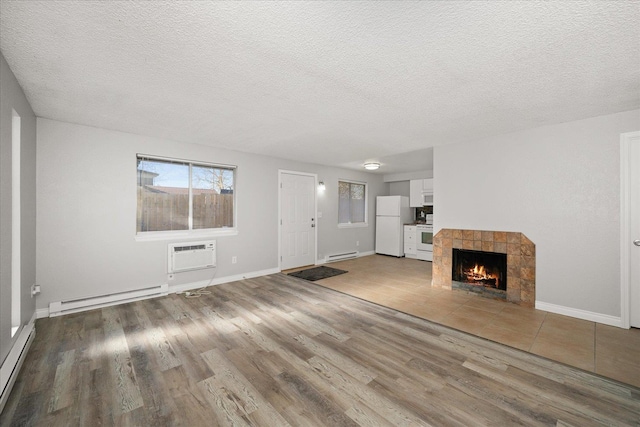 unfurnished living room featuring wood-type flooring, baseboard heating, and an AC wall unit