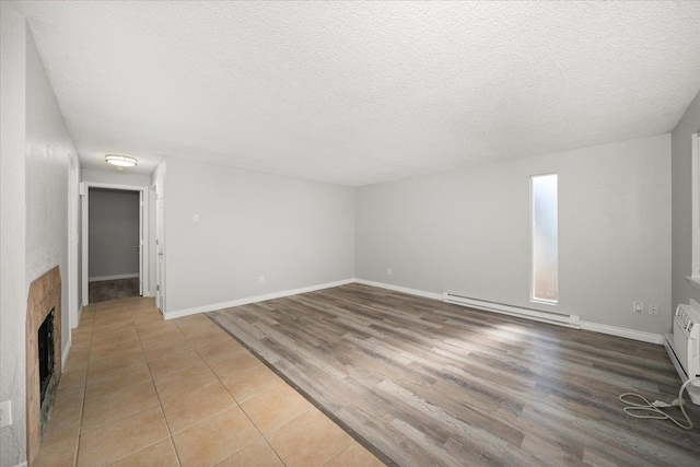 unfurnished living room featuring baseboard heating, a textured ceiling, and light wood-type flooring