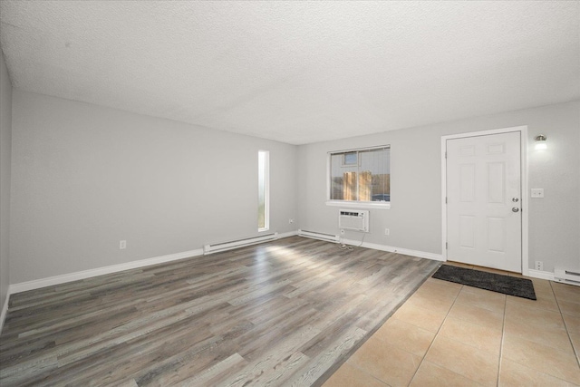 interior space with wood-type flooring, a baseboard radiator, a textured ceiling, and a wall unit AC