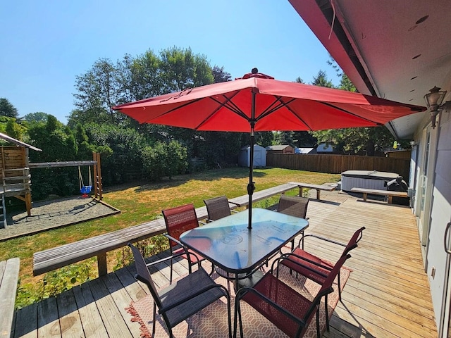 wooden deck with a lawn, a hot tub, and a storage unit