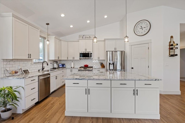 kitchen featuring white cabinets, appliances with stainless steel finishes, a kitchen island, decorative light fixtures, and vaulted ceiling