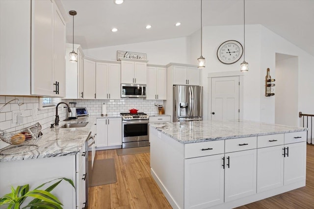 kitchen featuring a center island, decorative light fixtures, white cabinetry, stainless steel appliances, and sink