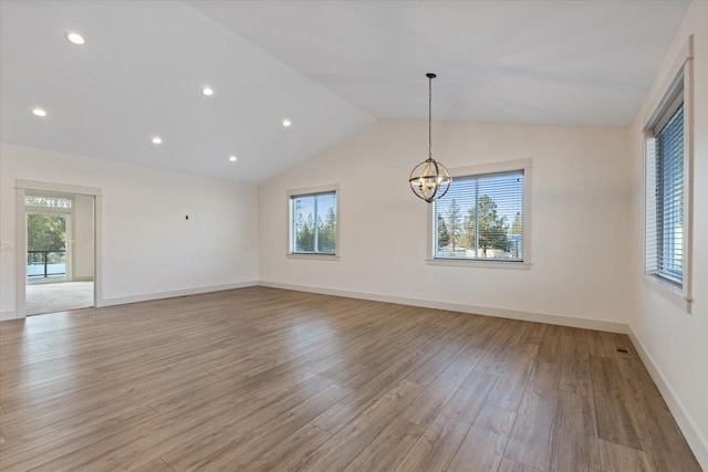 unfurnished room featuring light hardwood / wood-style flooring, a chandelier, and vaulted ceiling