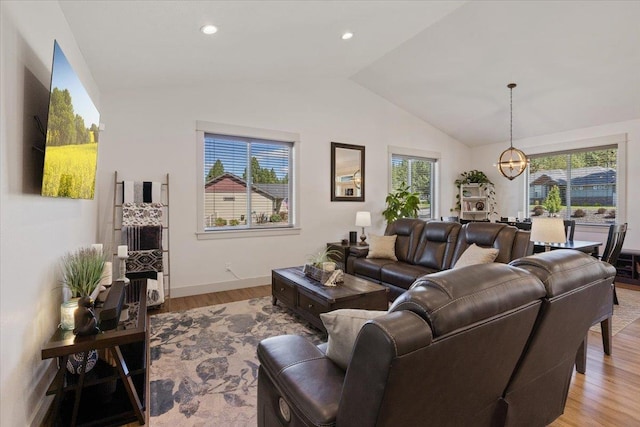 living room featuring light hardwood / wood-style floors, a notable chandelier, and vaulted ceiling