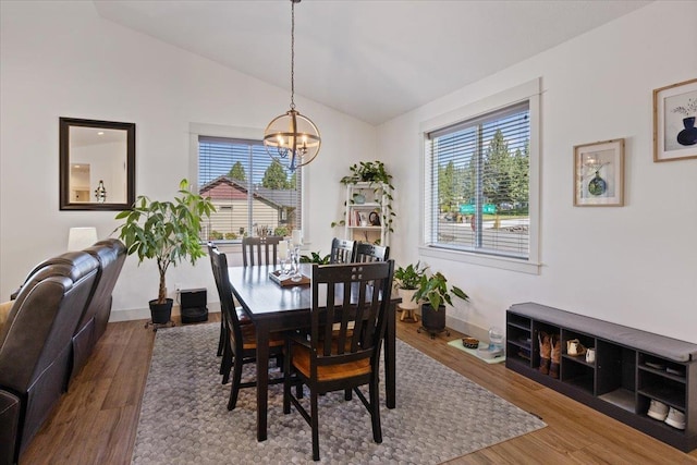 dining room with hardwood / wood-style flooring, a chandelier, and vaulted ceiling