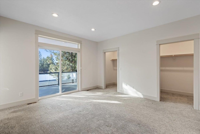 unfurnished bedroom featuring a closet, a spacious closet, access to outside, and light carpet