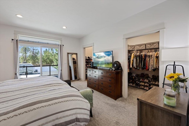 bedroom featuring access to outside, a walk in closet, a closet, and light carpet