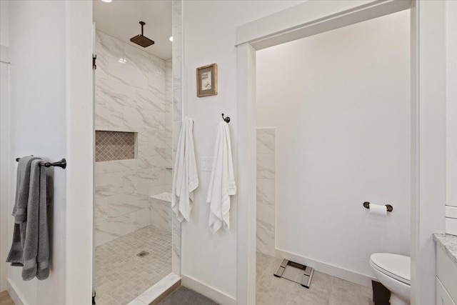 bathroom featuring a tile shower, toilet, and tile patterned floors