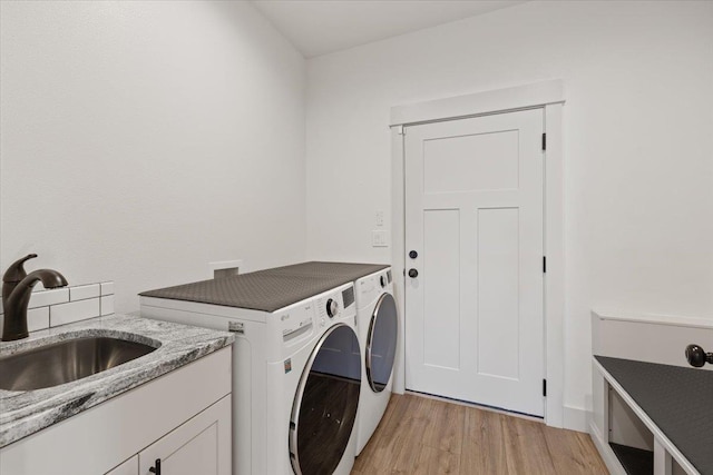 laundry area with sink, light wood-type flooring, and washing machine and clothes dryer