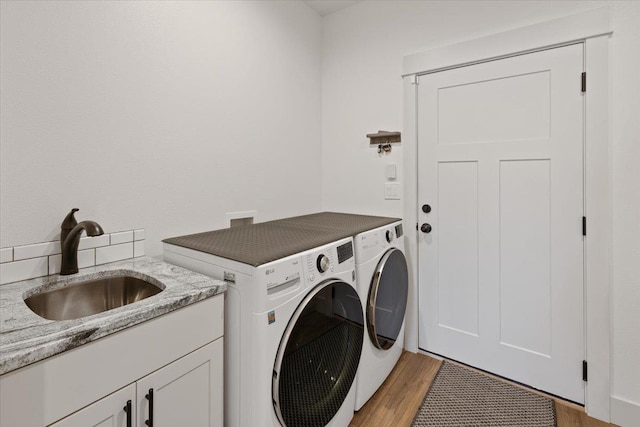 laundry room with sink, cabinets, light hardwood / wood-style flooring, and washer and dryer