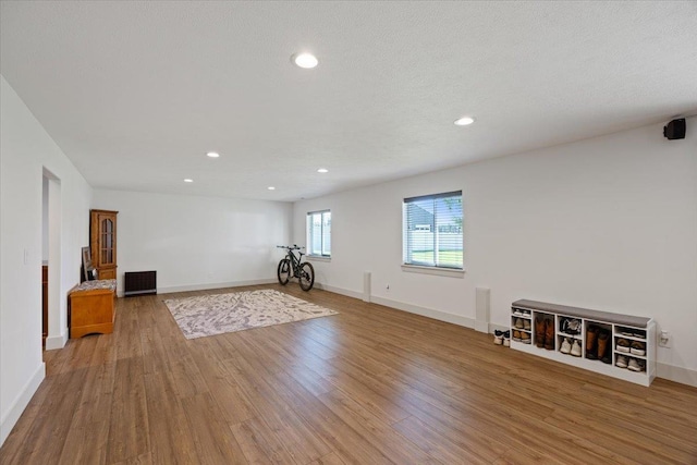 workout room with light wood-type flooring and a textured ceiling