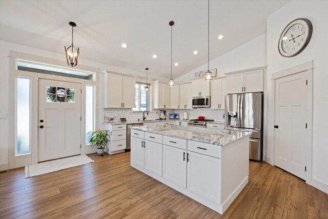 kitchen featuring white cabinetry, a center island, hanging light fixtures, and appliances with stainless steel finishes