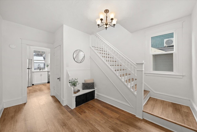 stairway with hardwood / wood-style flooring, sink, and a notable chandelier