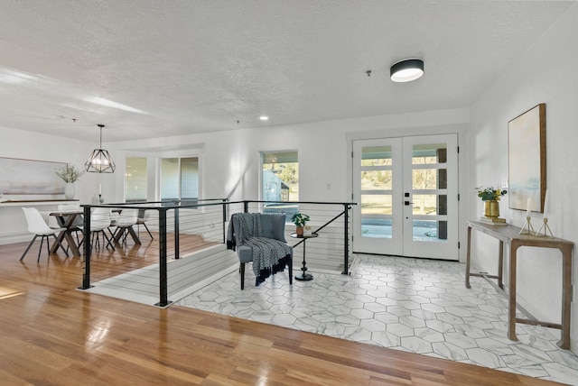 interior space with french doors, light hardwood / wood-style flooring, and a textured ceiling