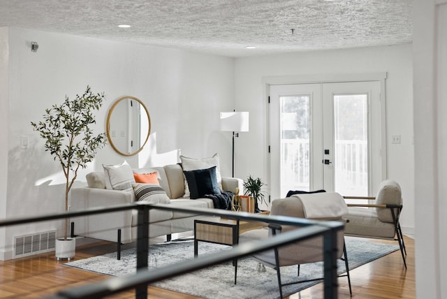 living room with hardwood / wood-style floors, a textured ceiling, and french doors