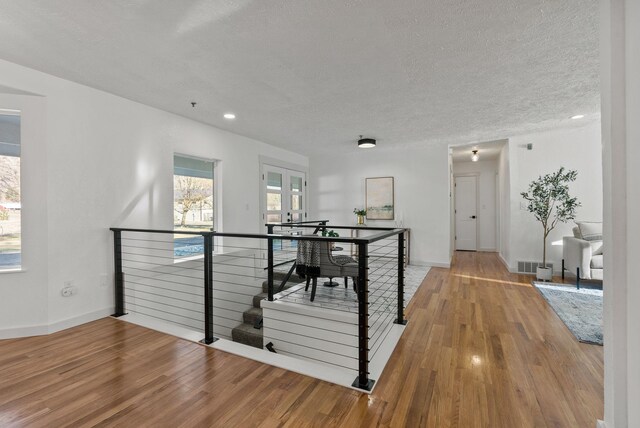 hallway with light hardwood / wood-style floors and a textured ceiling