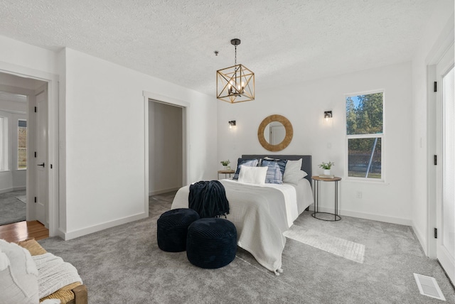 bedroom with a chandelier, multiple windows, light colored carpet, and a textured ceiling