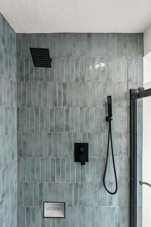 details with a textured ceiling and tiled shower