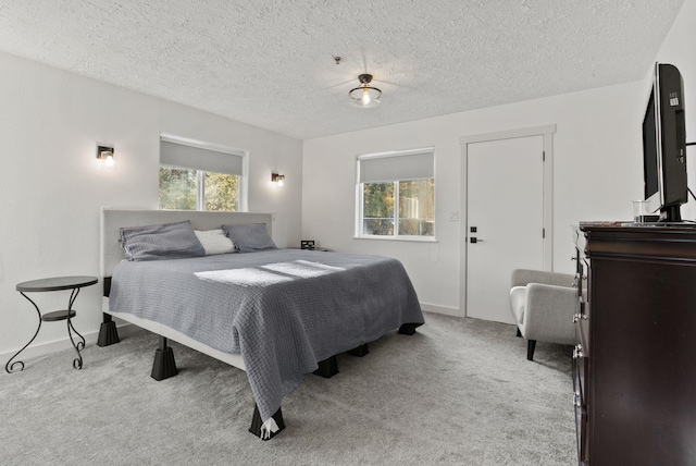 bedroom with light colored carpet and a textured ceiling