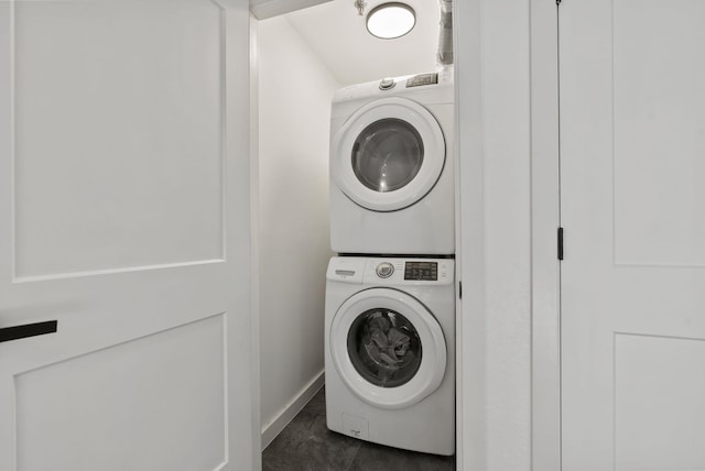 washroom with dark tile patterned floors and stacked washer and dryer