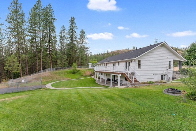 back of house with a deck, a yard, and a fire pit