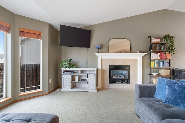 living room with a tile fireplace, carpet flooring, and lofted ceiling