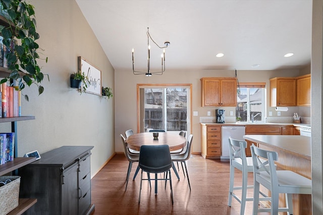 kitchen featuring sink, dishwasher, light hardwood / wood-style flooring, and decorative light fixtures