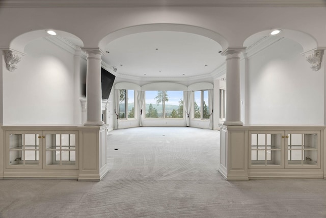 hallway with decorative columns, light colored carpet, and crown molding