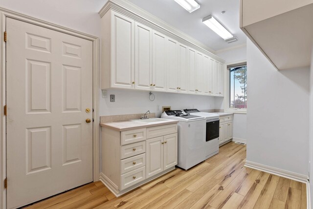 washroom with sink, washer / dryer, light hardwood / wood-style floors, and cabinets