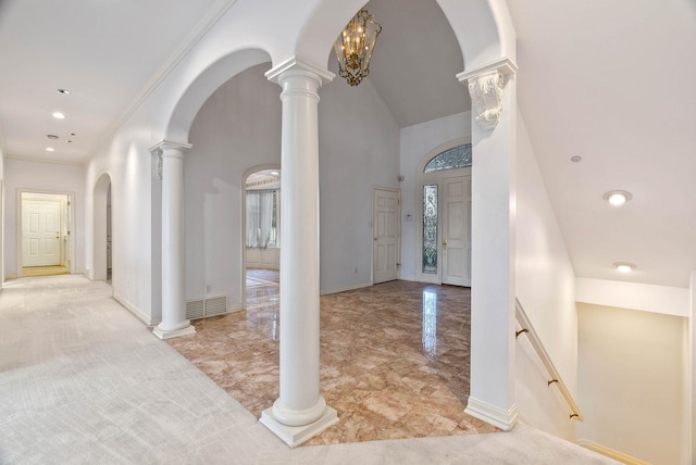 entrance foyer with decorative columns, a towering ceiling, and crown molding