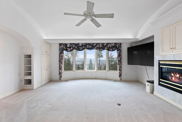 unfurnished living room with ceiling fan, light colored carpet, vaulted ceiling, and a fireplace