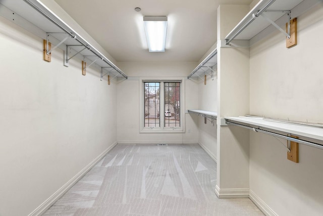 walk in closet featuring light colored carpet