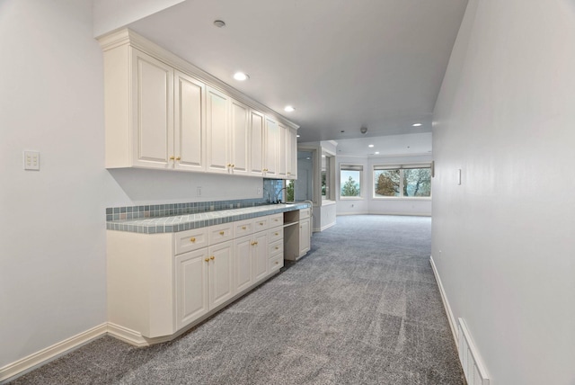 kitchen featuring sink, carpet, white cabinets, and tile counters