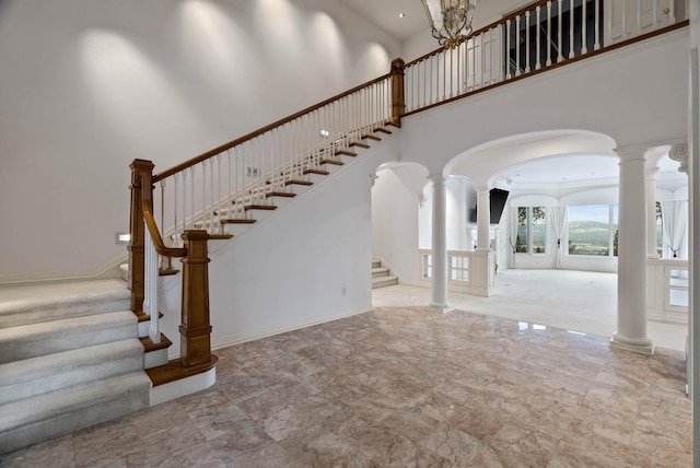 stairway featuring a towering ceiling and ornate columns