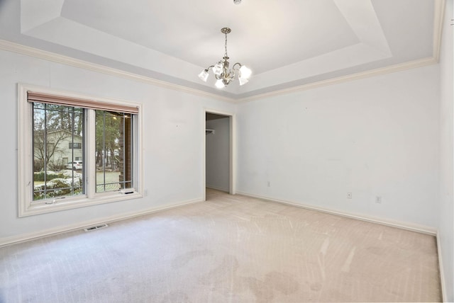 carpeted empty room with a raised ceiling and a notable chandelier