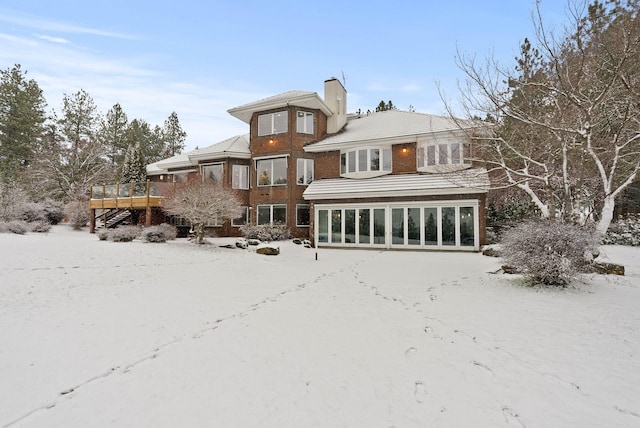 snow covered back of property with a wooden deck