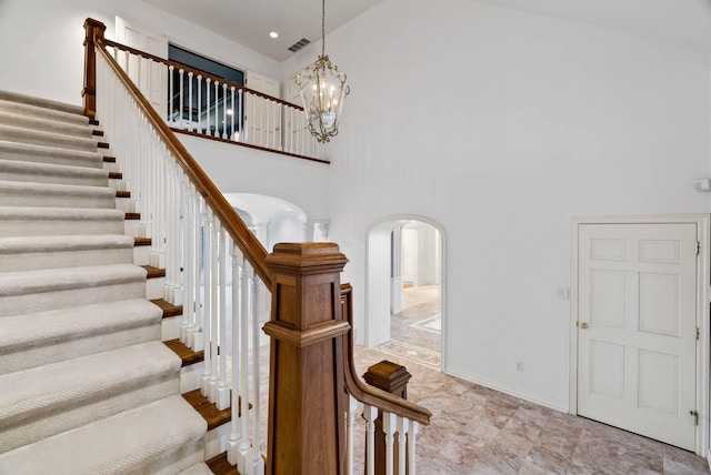 stairway featuring a towering ceiling and a chandelier