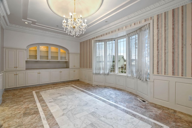 unfurnished dining area featuring a chandelier, a raised ceiling, and crown molding