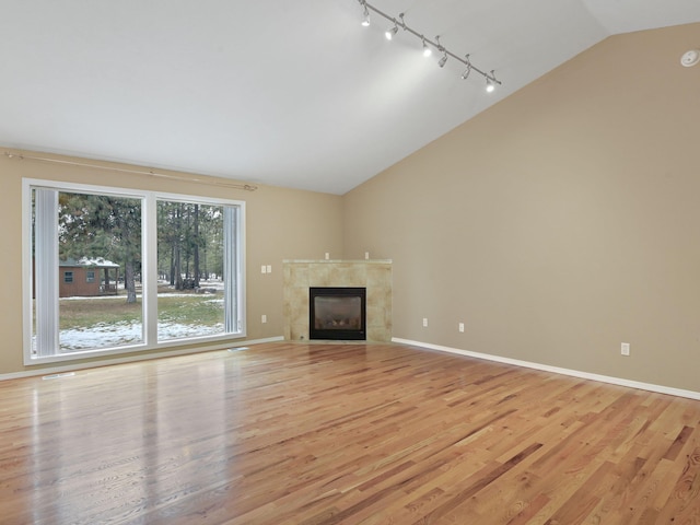 unfurnished living room with light wood-type flooring, a tile fireplace, and lofted ceiling