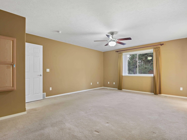 unfurnished room with ceiling fan, light colored carpet, and a textured ceiling