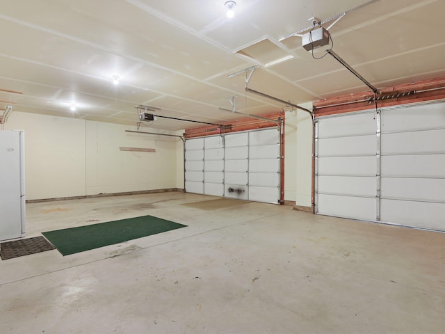 garage featuring white fridge and a garage door opener