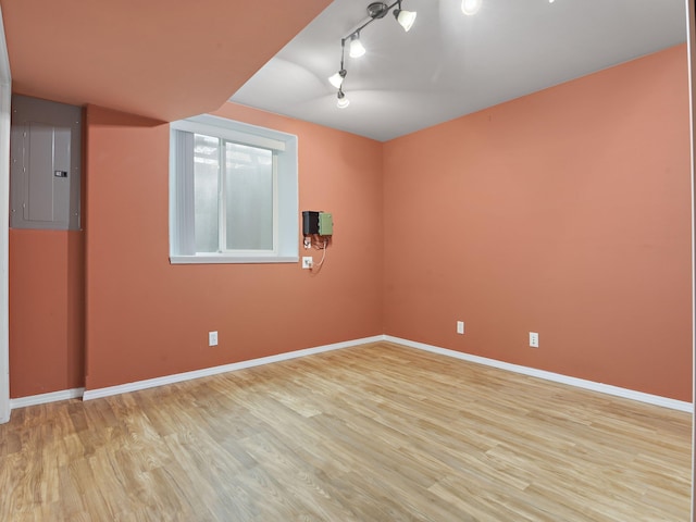 empty room with light hardwood / wood-style flooring, electric panel, and rail lighting