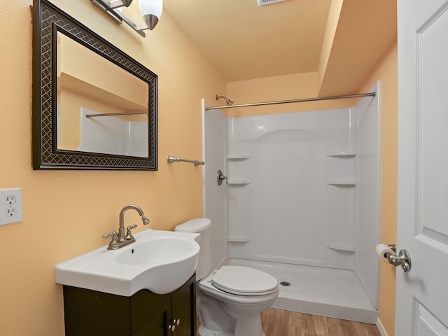 bathroom featuring vanity, hardwood / wood-style flooring, a shower, and toilet