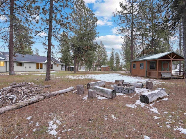 yard covered in snow featuring a fire pit and an outbuilding